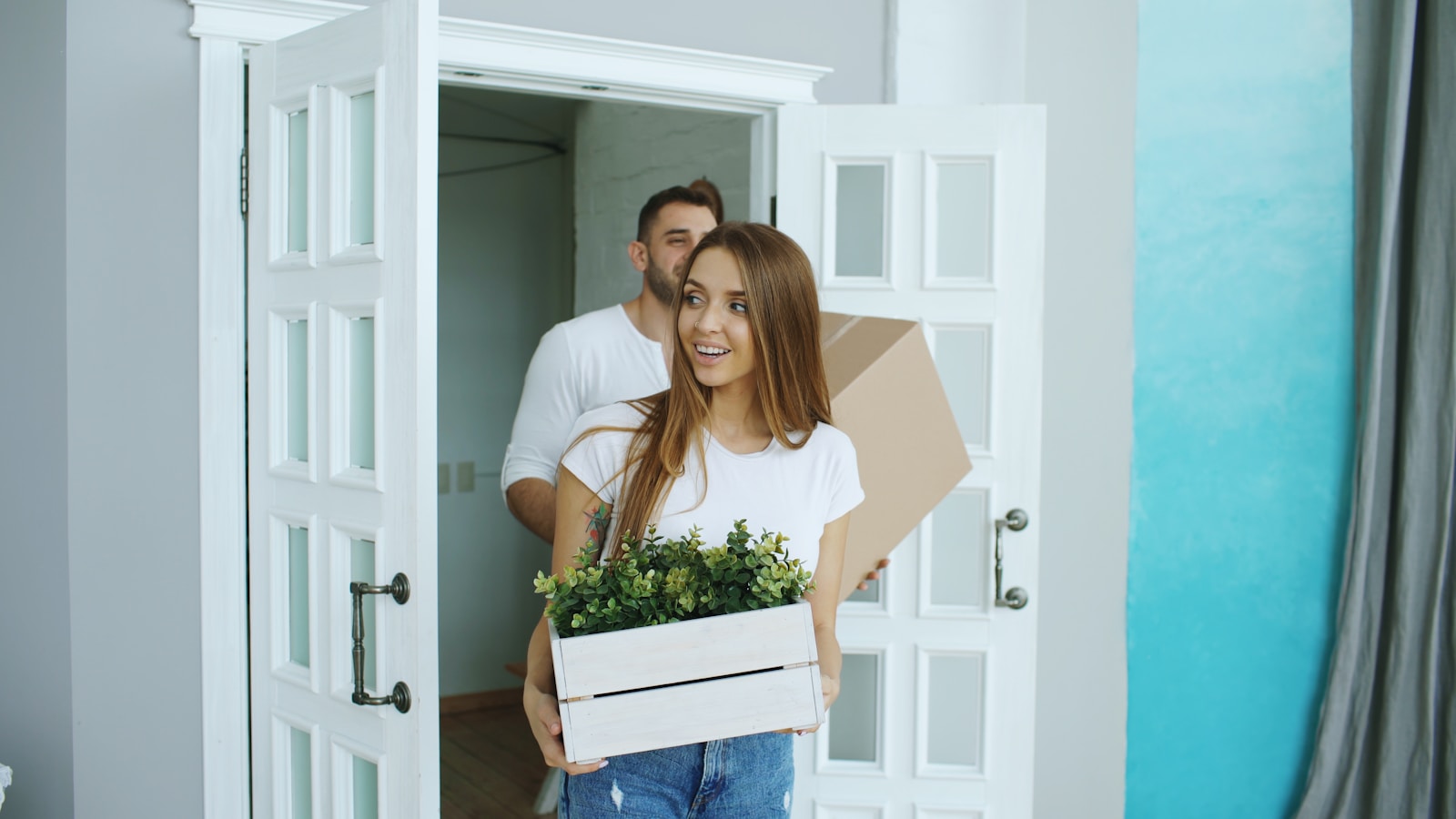 Couple carrying moving boxes into a home